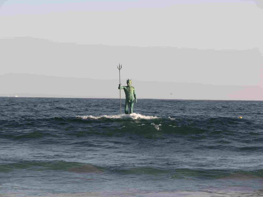 Estatua de Neptuno surgiendo del mar en la Playa de Melenara