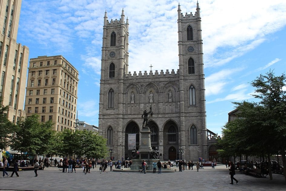 a large stone building with towers and a statue in front of it with Notre-Dame Basilica in the background