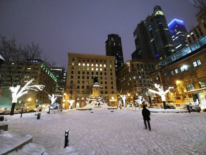 a city with buildings and a statue in the snow